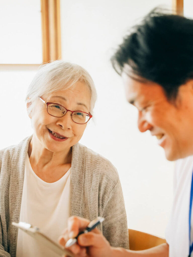高齢の女性がスタッフと一緒に書類を確認しながら話している様子