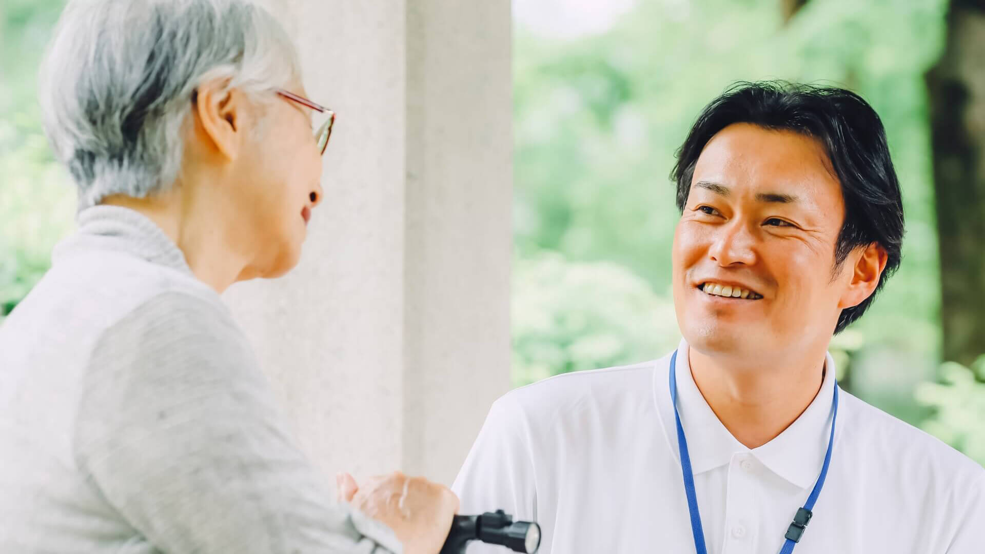 屋外で高齢の女性とスタッフが笑顔で会話している様子