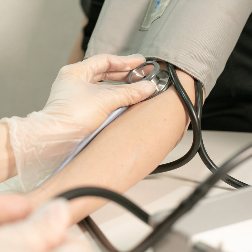 腕に巻いた血圧計を使い、聴診器で測定している手元の様子