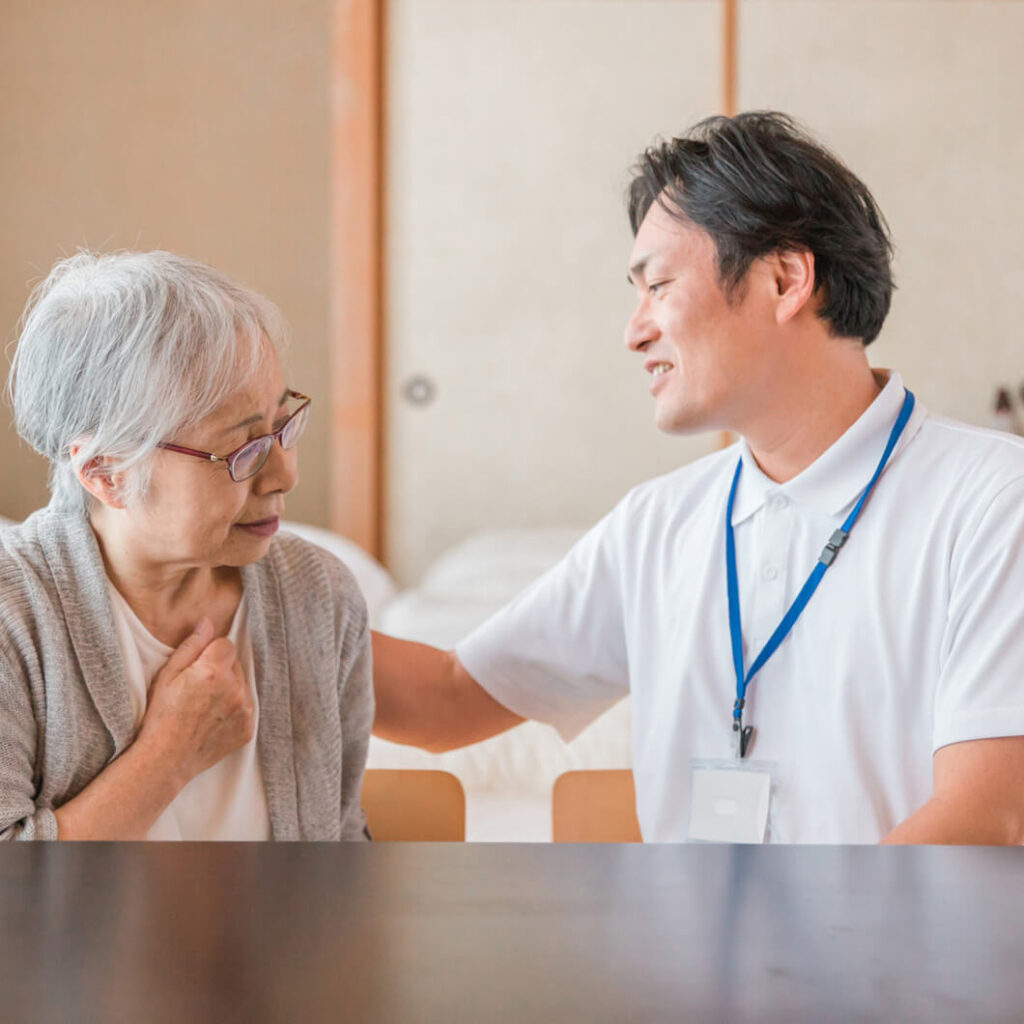 高齢の女性がスタッフと向かい合い、穏やかな表情で会話している様子